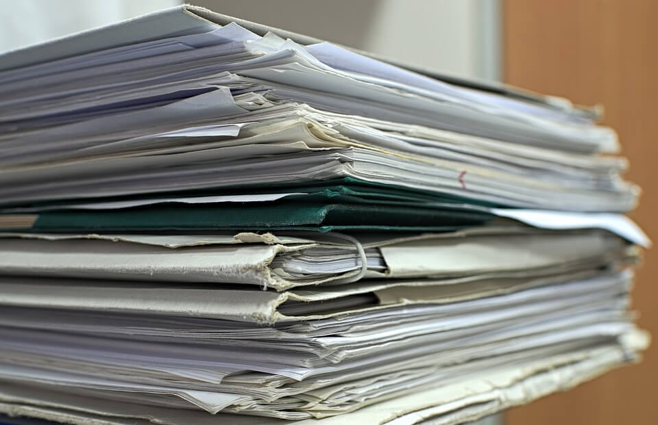 Pile de documents papiers à dématérialiser grâce à un logiciel GED
