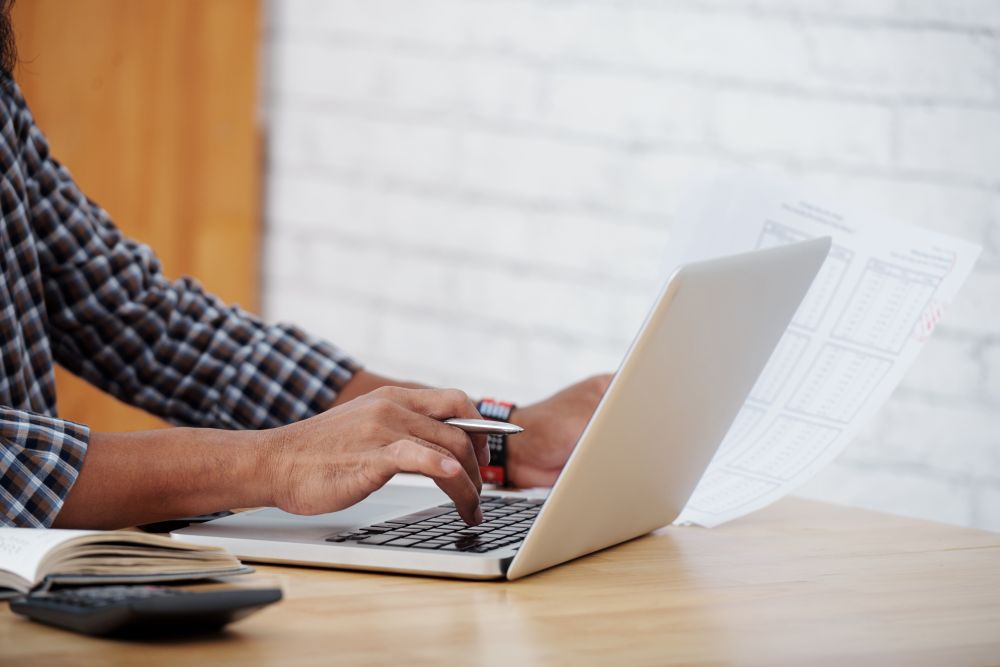 Un homme écrit sur un ordinateur portable